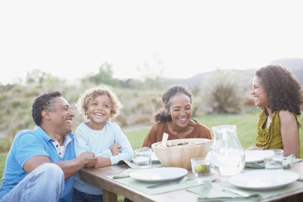 black family sitting around a table outside happy